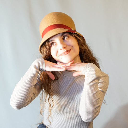 Daize cloche hat in camel wool felt with red ribbon and gold lyre by Anna Xaniotaki