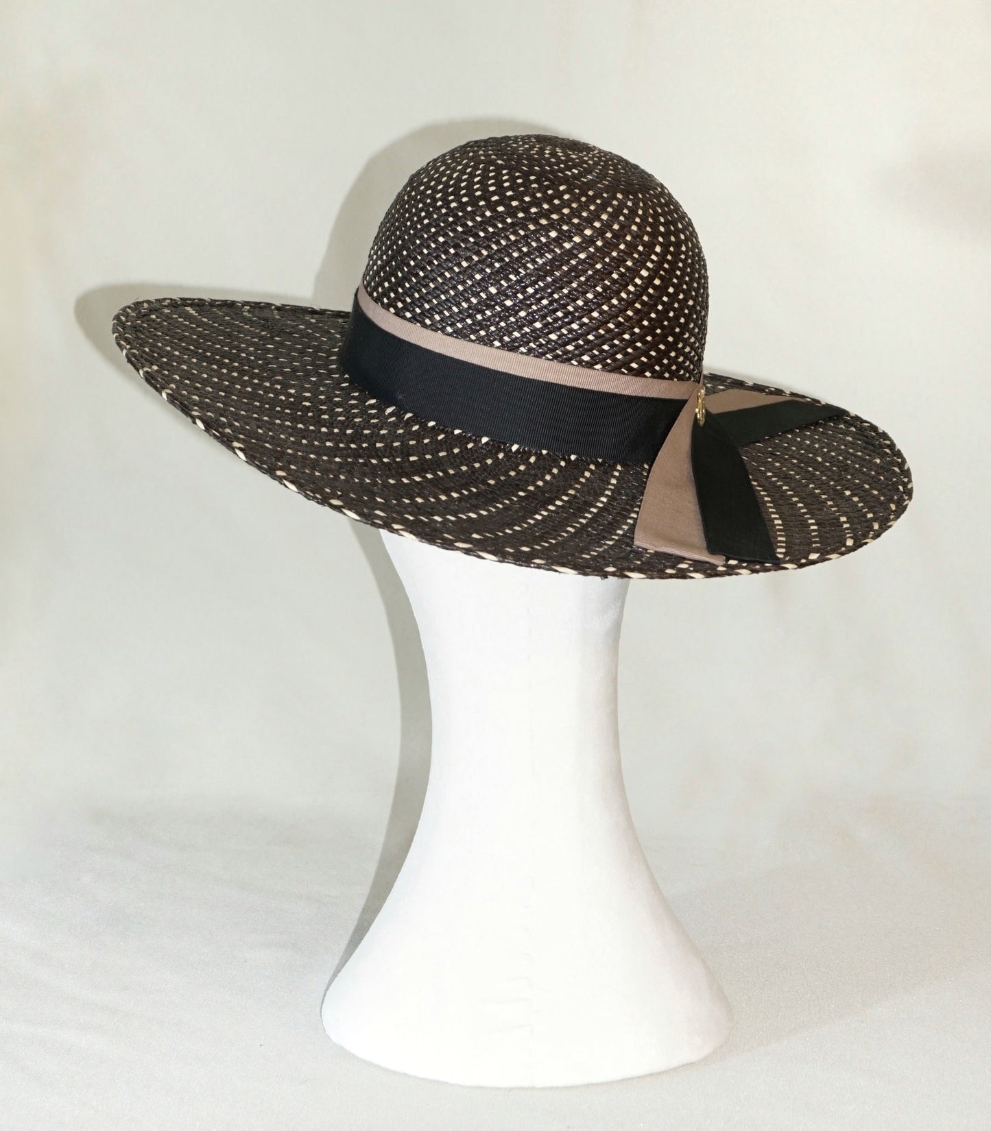 Black and ivory Panama hat with black and nude blush ribbons and gold lyre emblem, three-quarter back view by Anna Xaniotaki