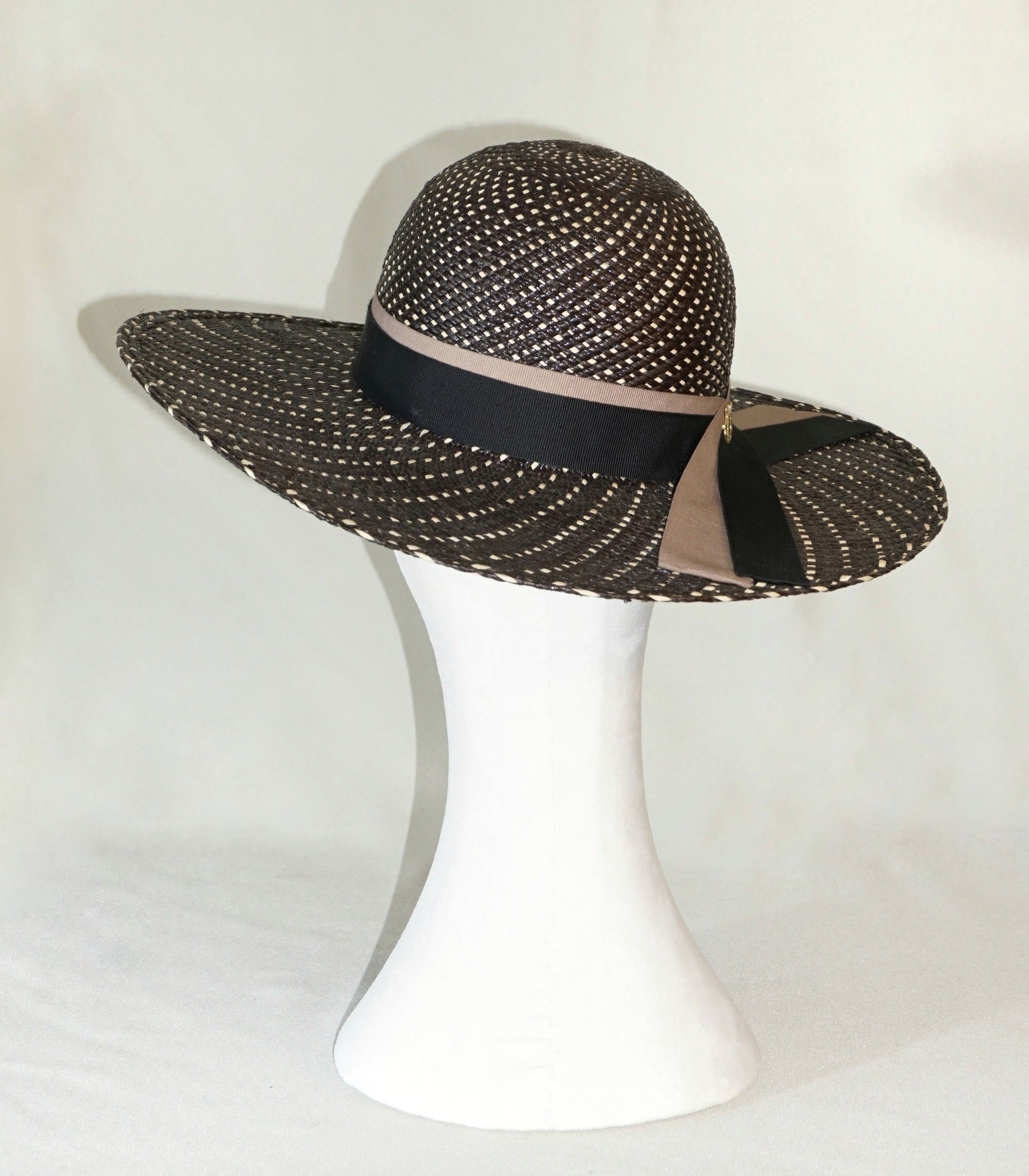 Black and ivory Panama hat with black and nude blush ribbons and gold lyre emblem, three-quarter back view by Anna Xaniotaki