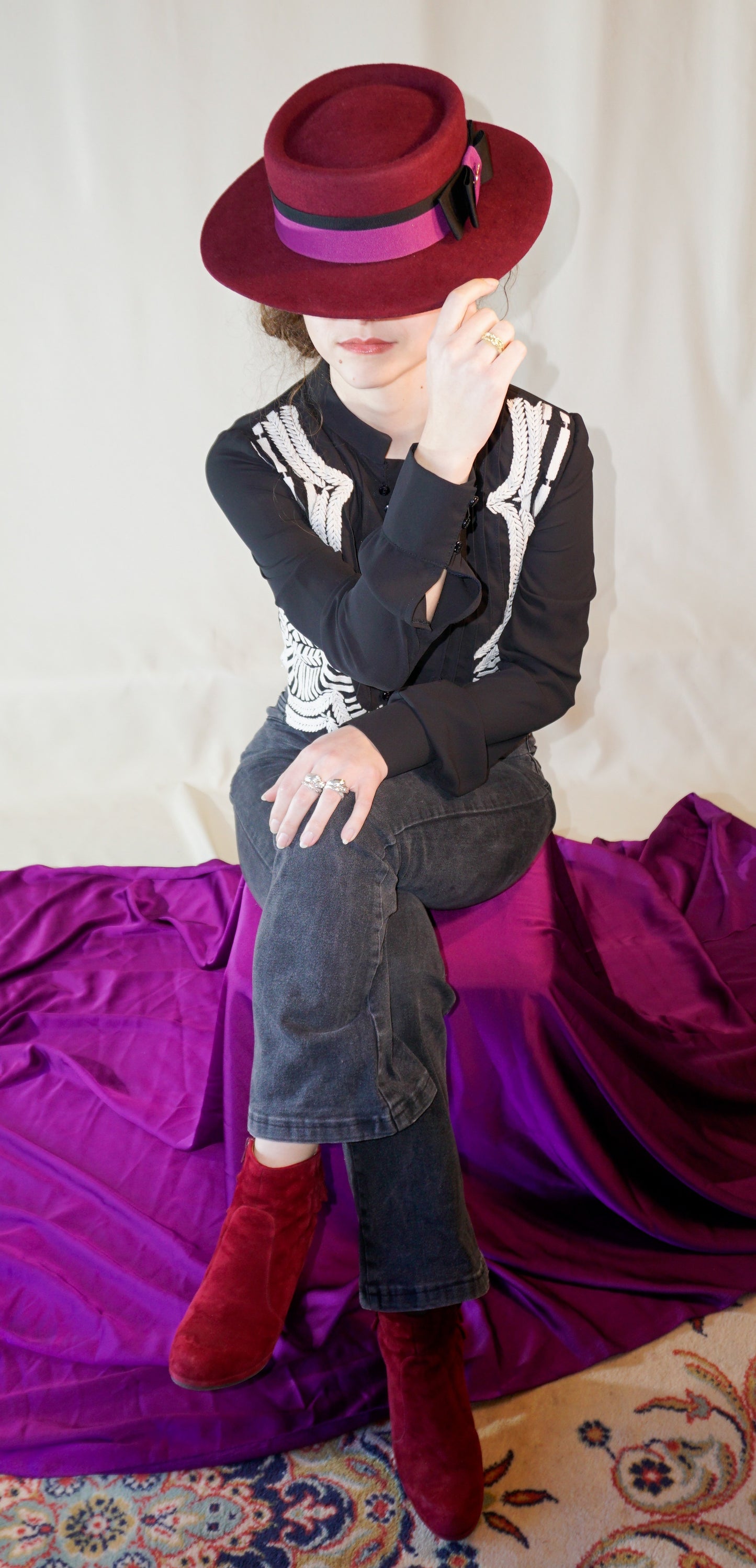 Woman wearing Scarlet Ode burgundy boater hat - luxury handcrafted millinery by Anna Xaniotaki