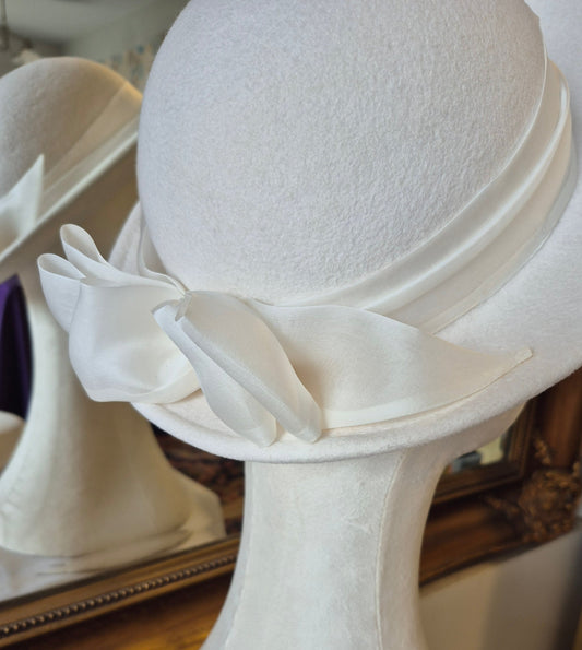 Ivory felt halo hat with silk organza bow by Anna Xaniotaki, three quarter view by Anna Xaniotaki