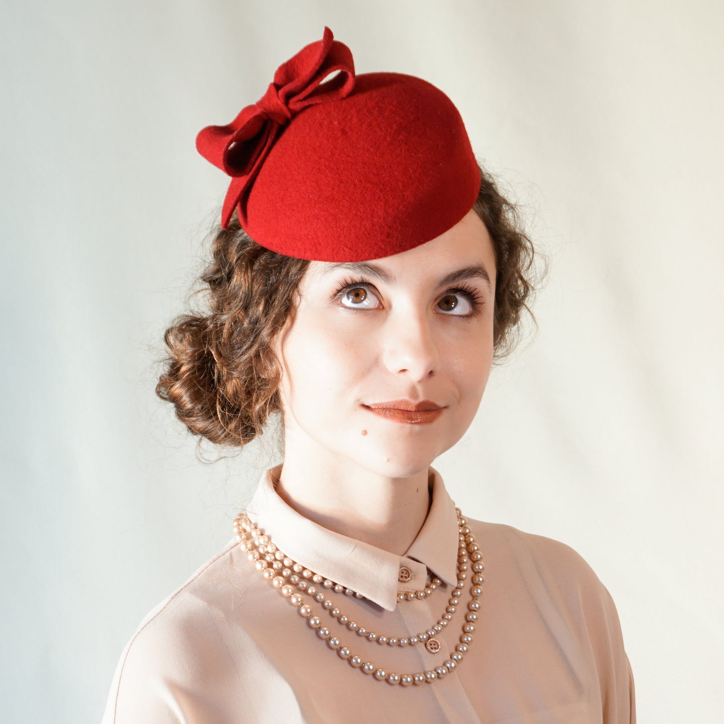 Erato Ode red felt pillbox hat with handmade felt bow and 14ct gold-plated silver lyre by Anna Xaniotaki - front three-quarter view