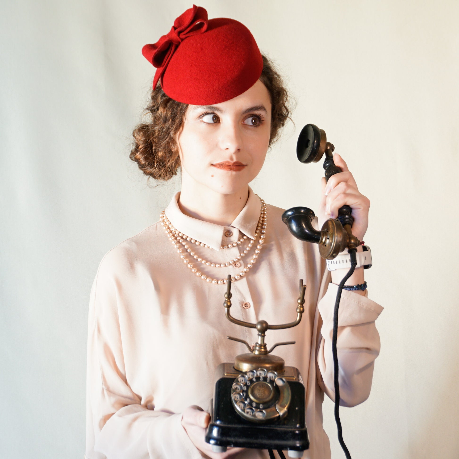 Erato Ode red felt pillbox hat with handmade felt bow and 14ct gold-plated silver lyre by Anna Xaniotaki - front left three-quarter view - front angle view
