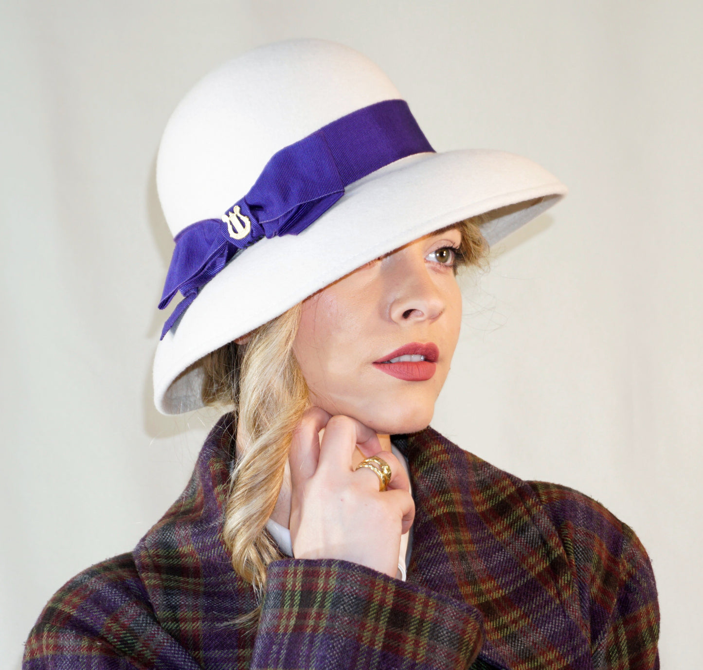 Blanche Élégance white felt hat with purple grosgrain bow and golden lyre by Anna Xaniotaki, right three-quarter view