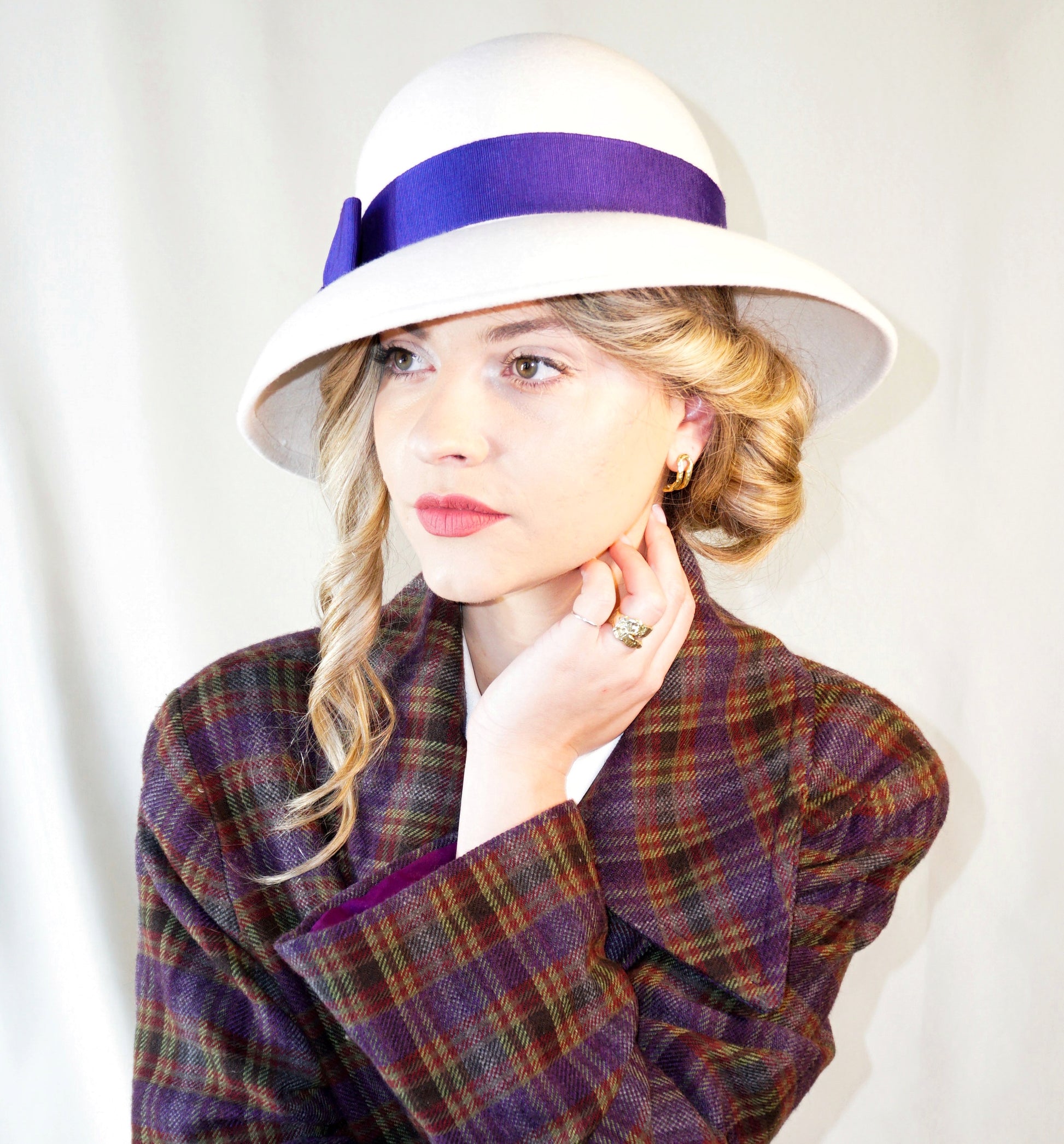 Blanche Élégance white felt hat with purple grosgrain bow and golden lyre by Anna Xaniotaki, left three-quarter front view
