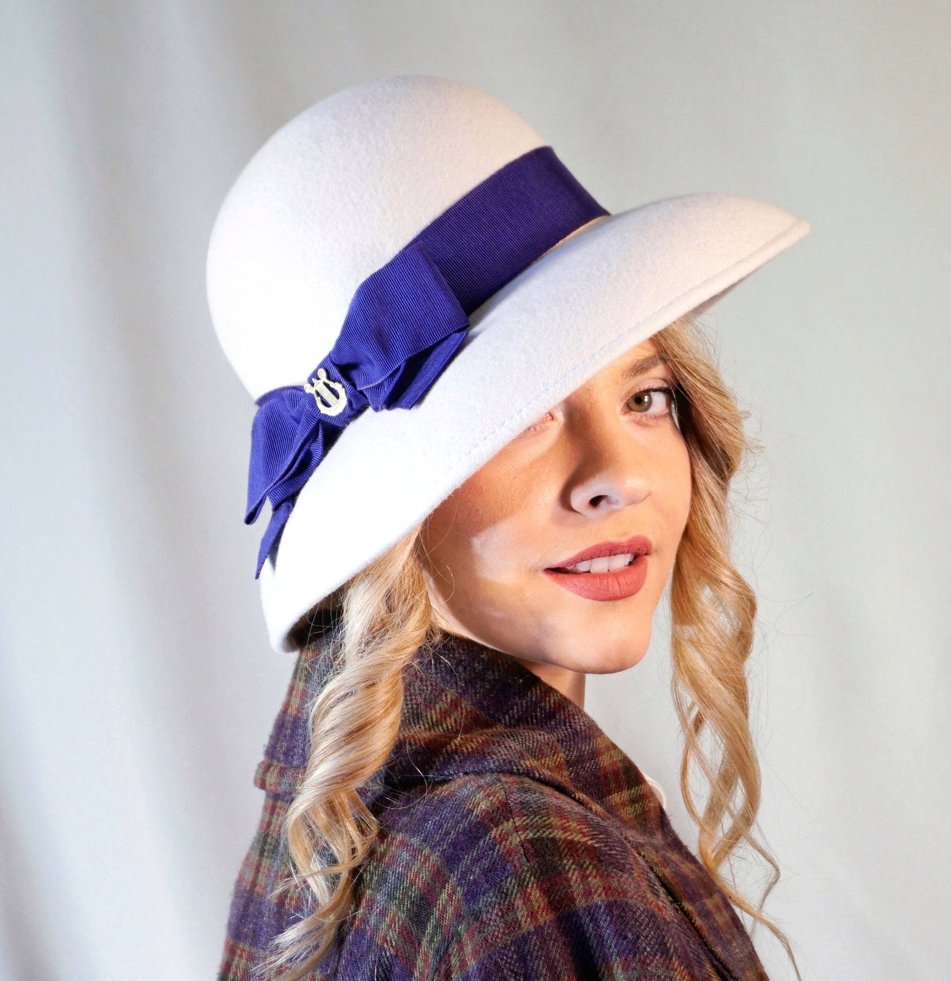 Blanche Élégance white felt hat with purple grosgrain bow and golden lyre by Anna Xaniotaki, right three-quarter view