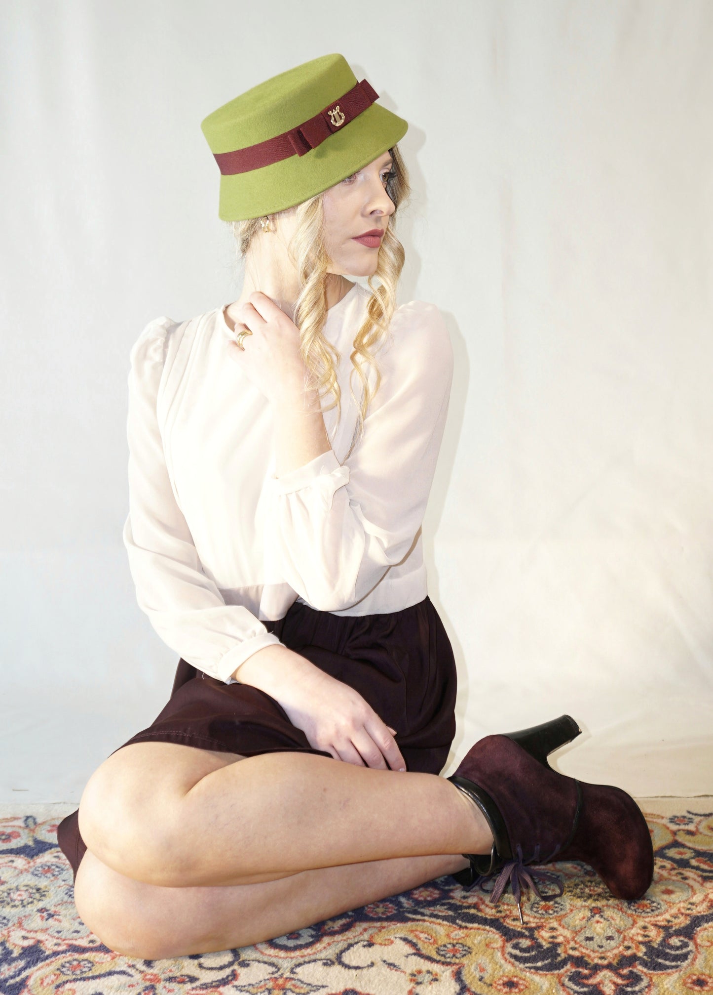 Aristocratic Melody lime pillbox felt hat with double burgundy bow and 14ct gold-plated silver lyre by Anna Xaniotaki - front three-quarter view