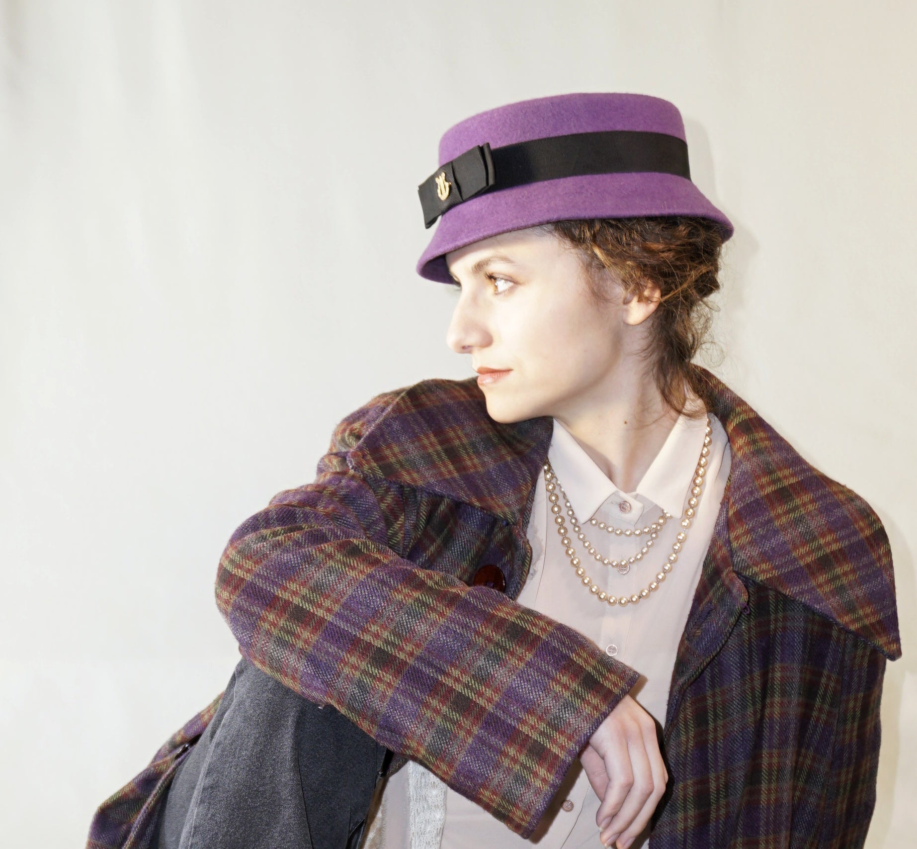 Aristocratic Melody Pillbox Hat in Royal Purple Wool Felt with Black Double Bow and Gold Lyre by Anna Xaniotaki - left side view