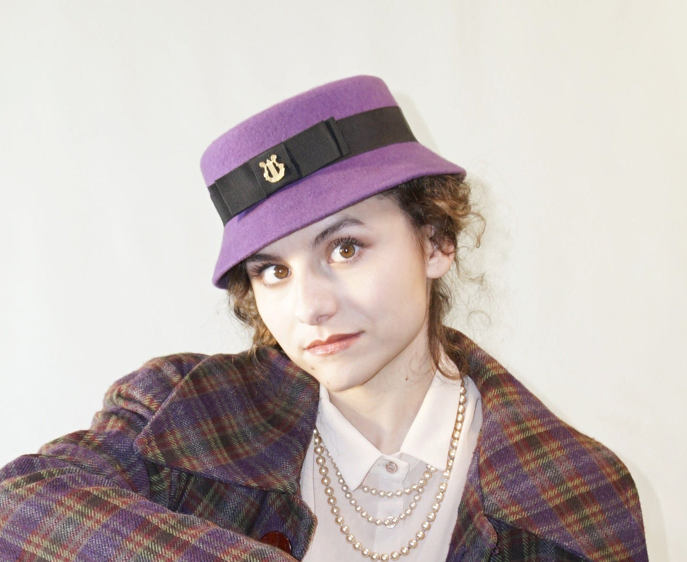 Aristocratic Melody Pillbox Hat in Royal Purple Wool Felt with Black Double Bow and Gold Lyre by Anna Xaniotaki - front view