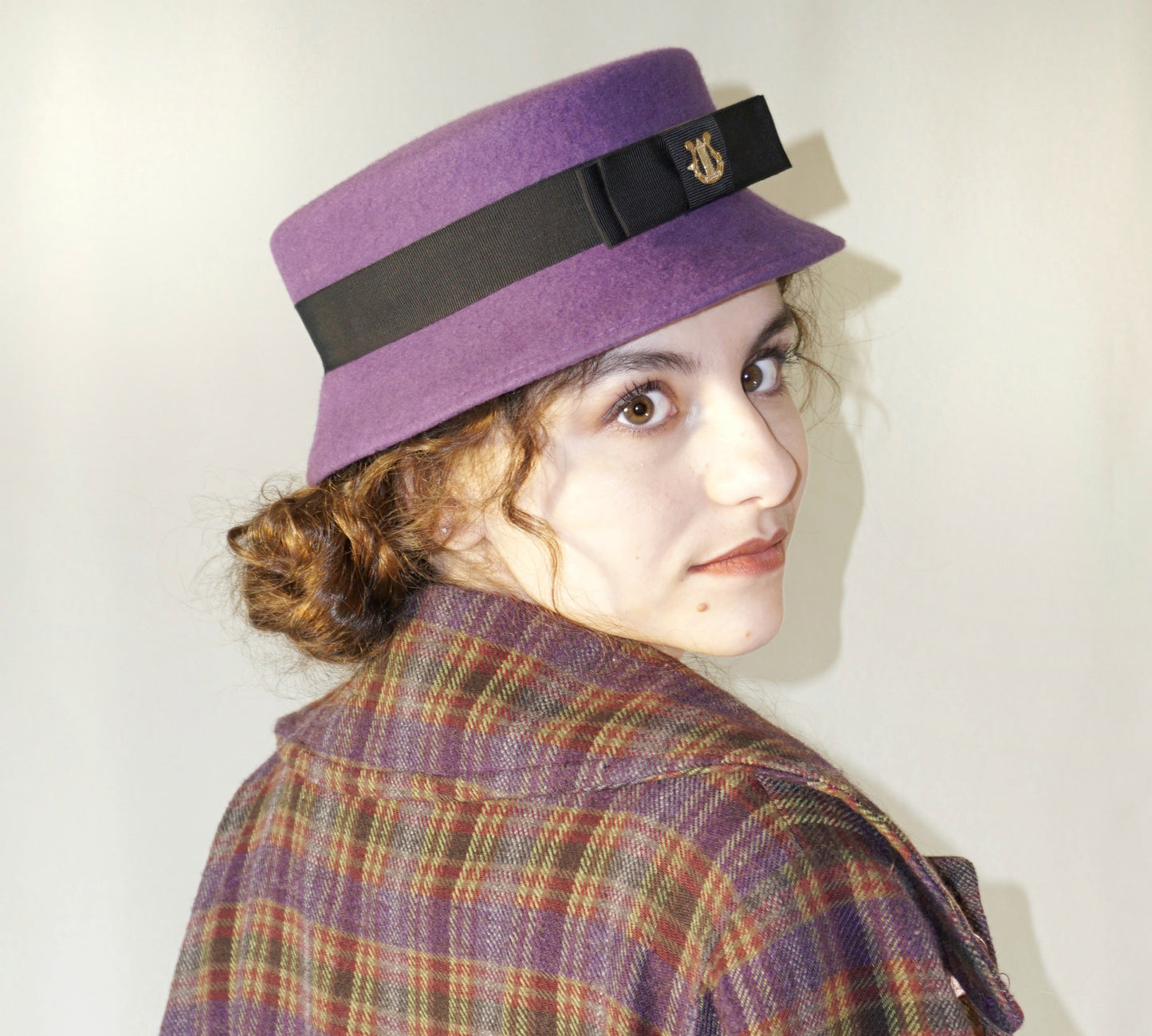 Aristocratic Melody Pillbox Hat in Royal Purple Wool Felt with Black Double Bow and Gold Lyre by Anna Xaniotaki - right side view