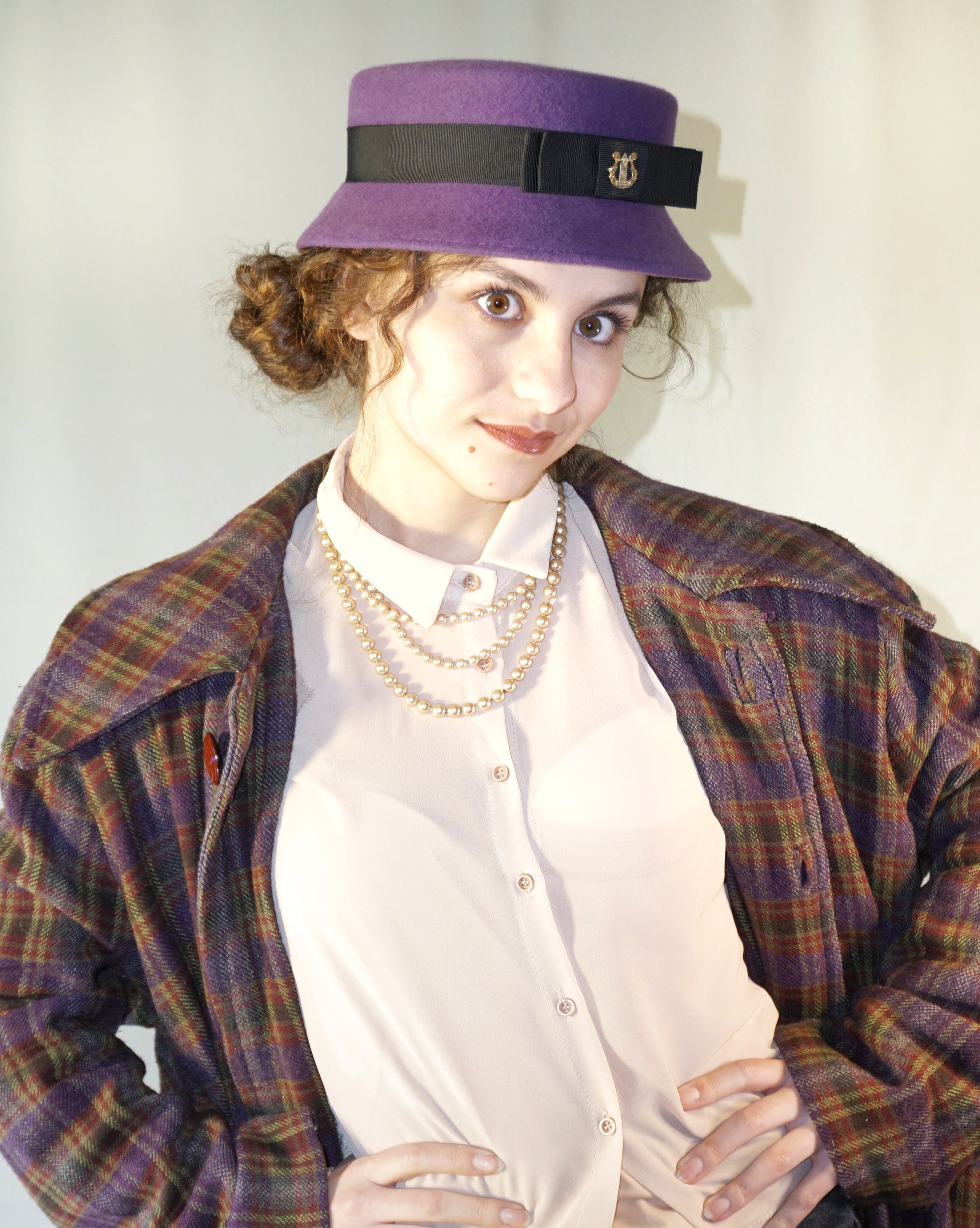 
Aristocratic Melody Pillbox Hat in Royal Purple Wool Felt with Black Double Bow and Gold Lyre by Anna Xaniotaki - three-quarter front right view