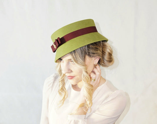 Aristocratic Melody pillbox in rabbit fur felt in pale green with a front burgundy Italian cotton grosgrain band and double bow and 14ct gold-plated silver lyre by Anna Xaniotaki - three-quarter left side view