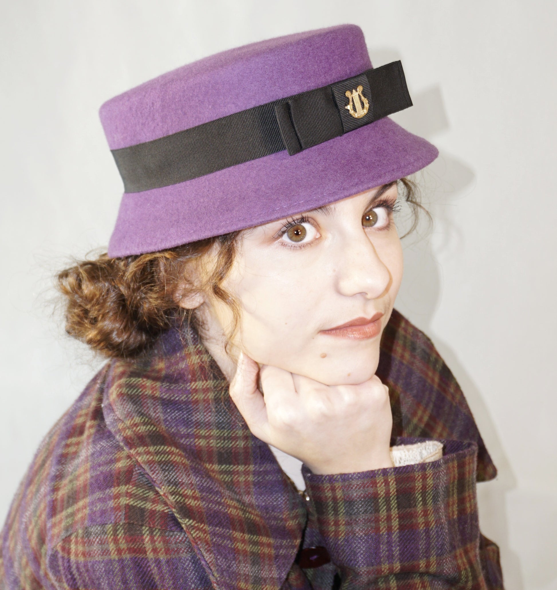 Aristocratic Melody Pillbox Hat in Royal Purple Wool Felt with Black Double Bow and Gold Lyre by Anna Xaniotaki - three-quarter front right  view
