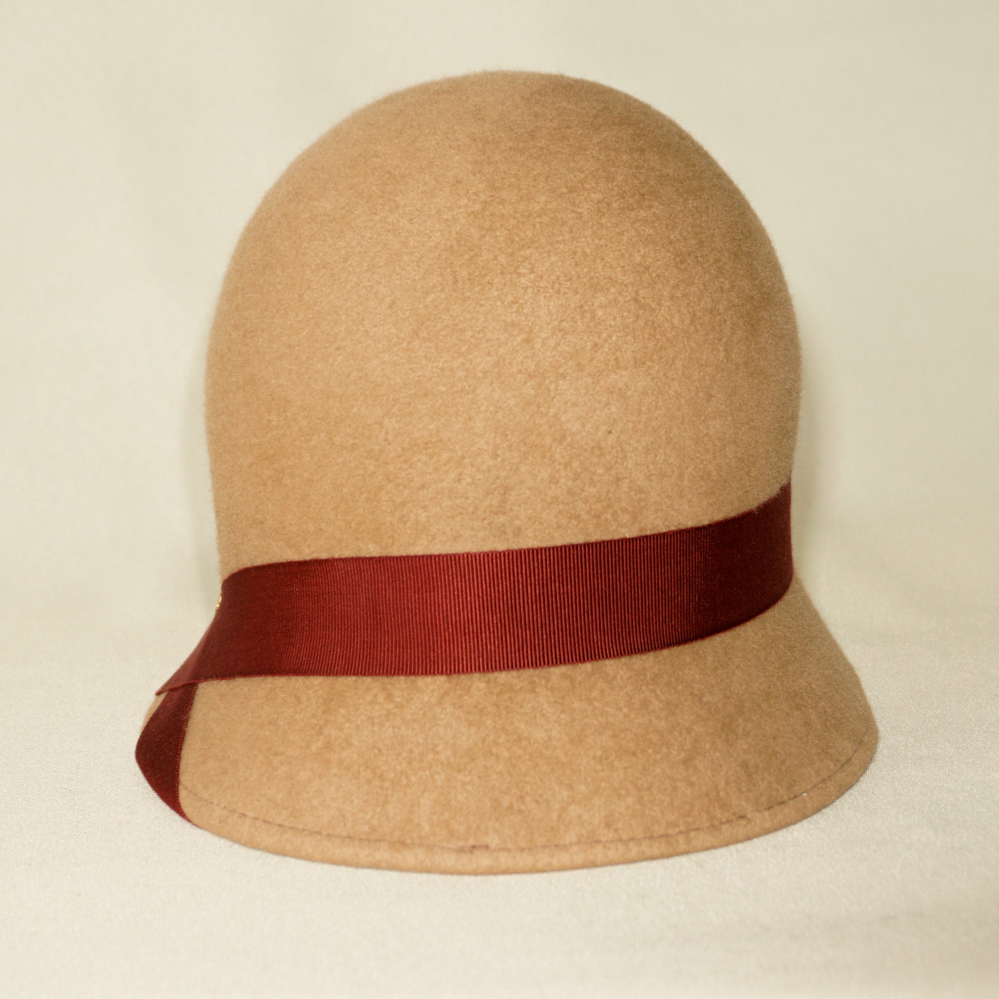 Daize cloche hat in camel wool felt with red ribbon and gold lyre by Anna Xaniotaki - front view
