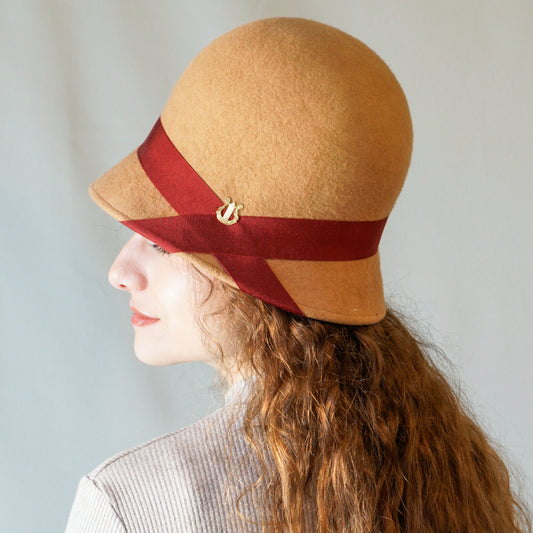Daize cloche hat in camel wool felt with red ribbon and gold lyre detail by Anna Xaniotaki