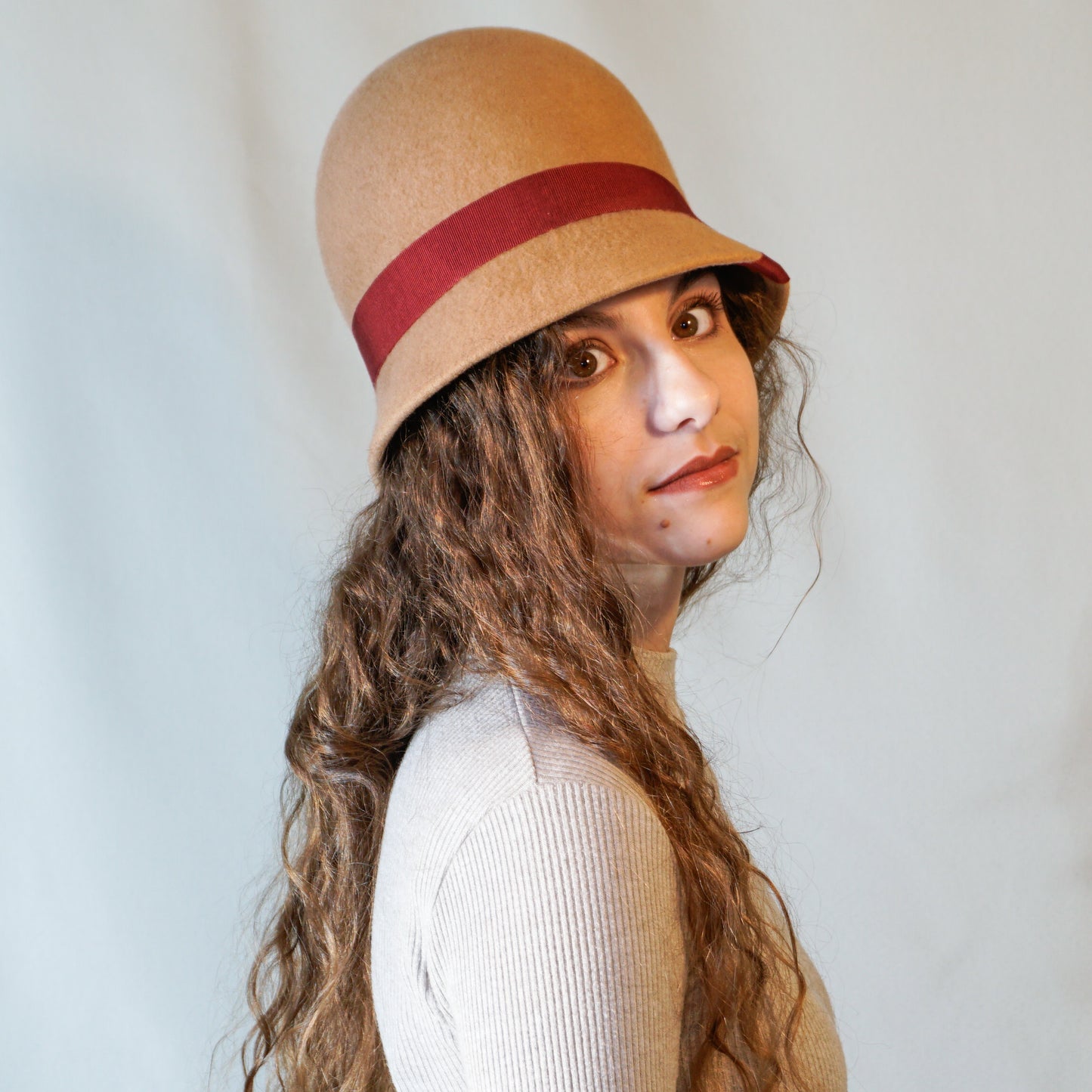 Daize cloche hat in camel wool felt with red ribbon and gold lyre by Anna Xaniotaki - three quarter side view