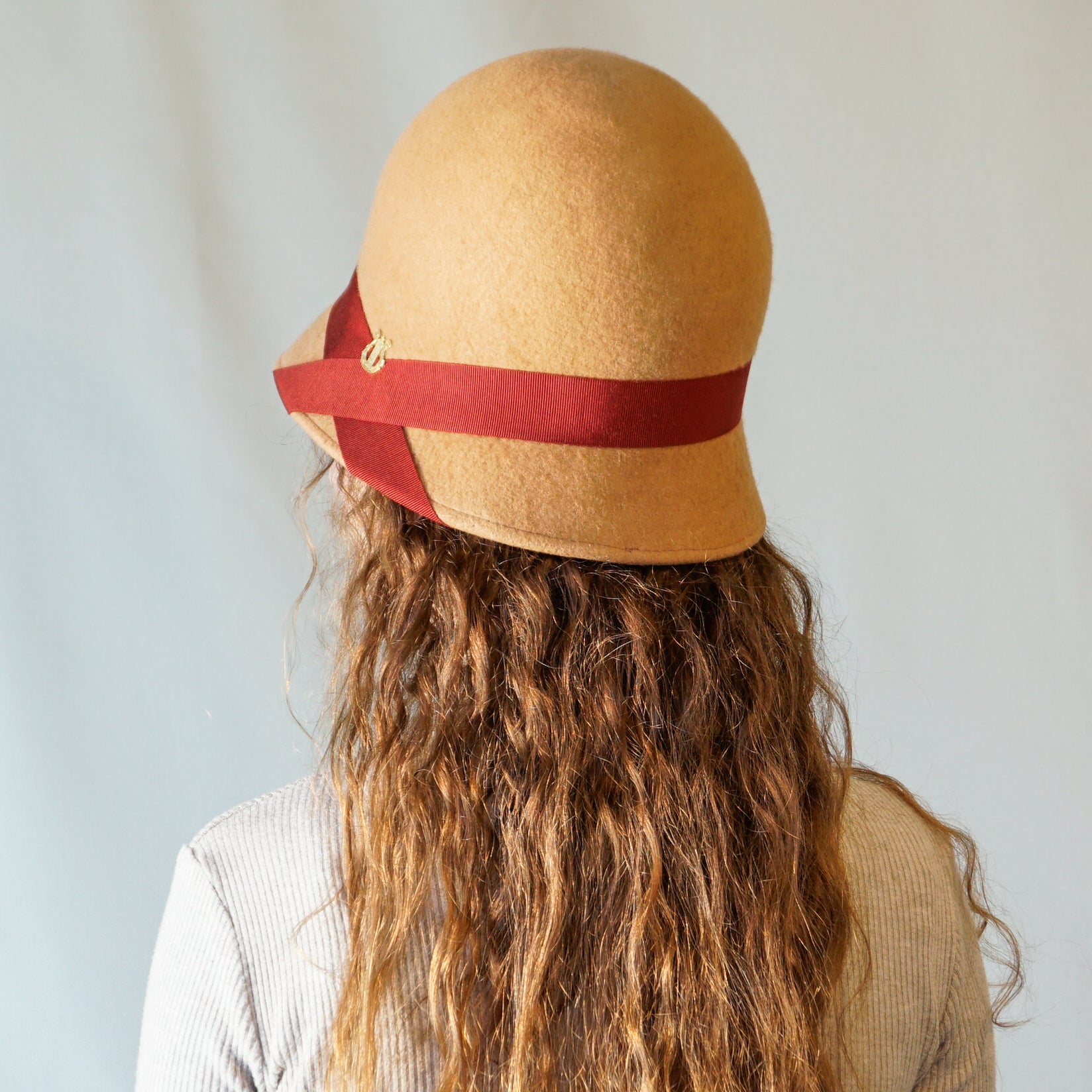 Daize cloche hat in camel wool felt with red ribbon and gold lyre by Anna Xaniotaki - back view