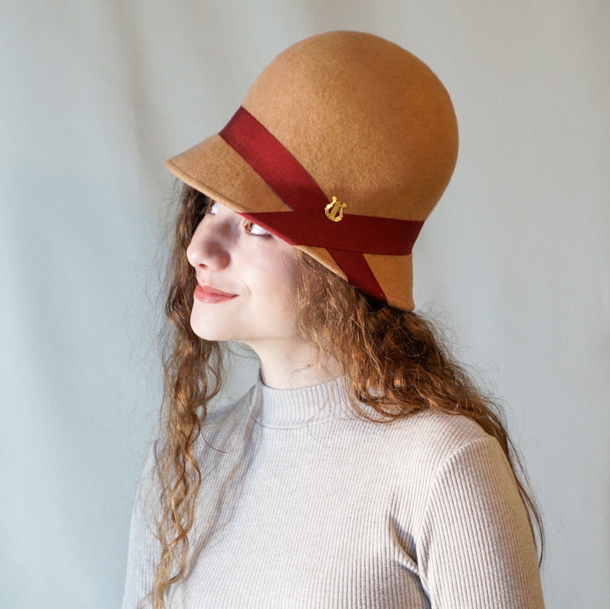 Daize cloche hat in camel wool felt with red ribbon and gold lyre by Anna Xaniotaki - side view