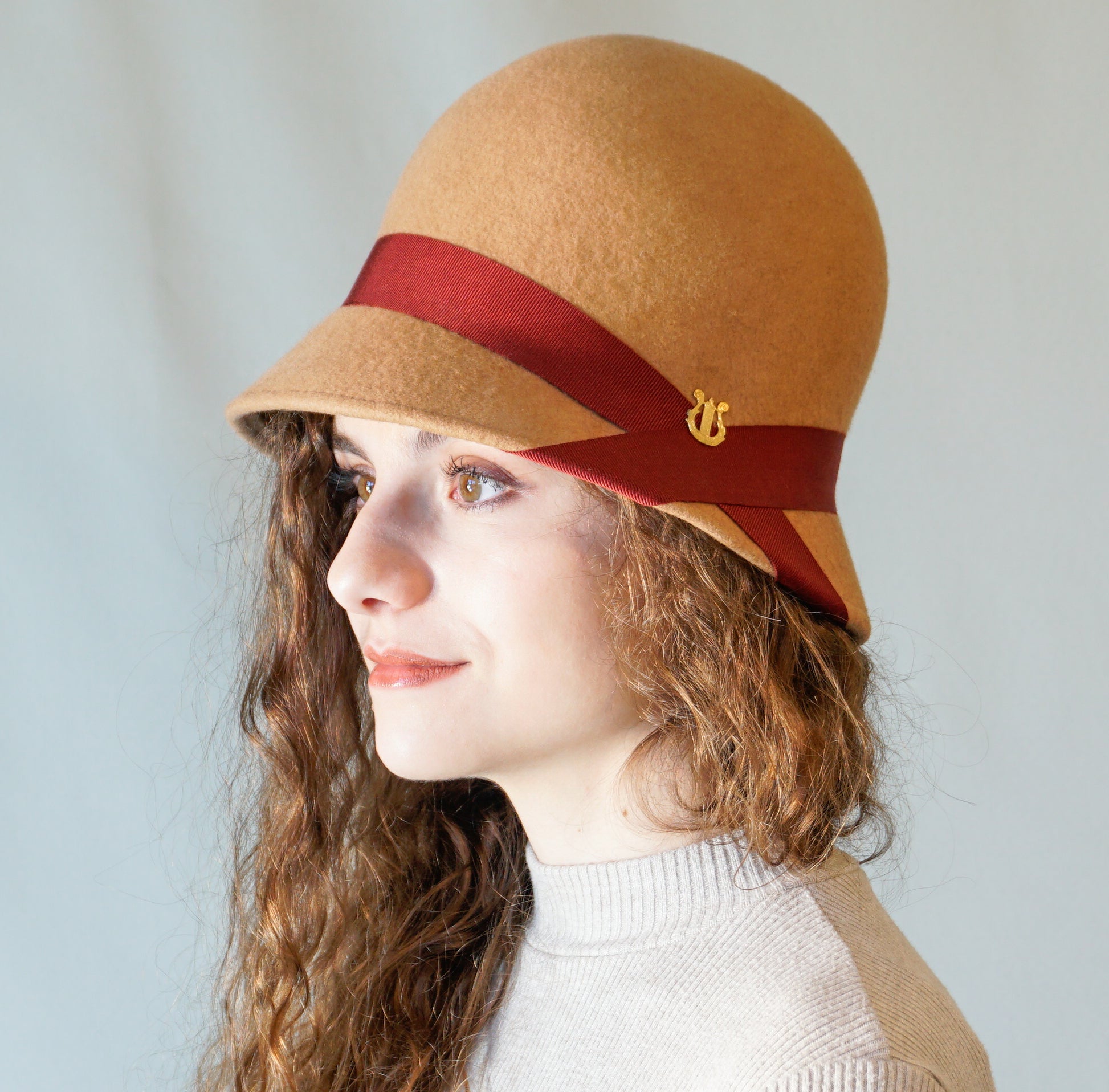 Daize cloche hat in camel wool felt with red ribbon and gold lyre by Anna Xaniotaki - side view
