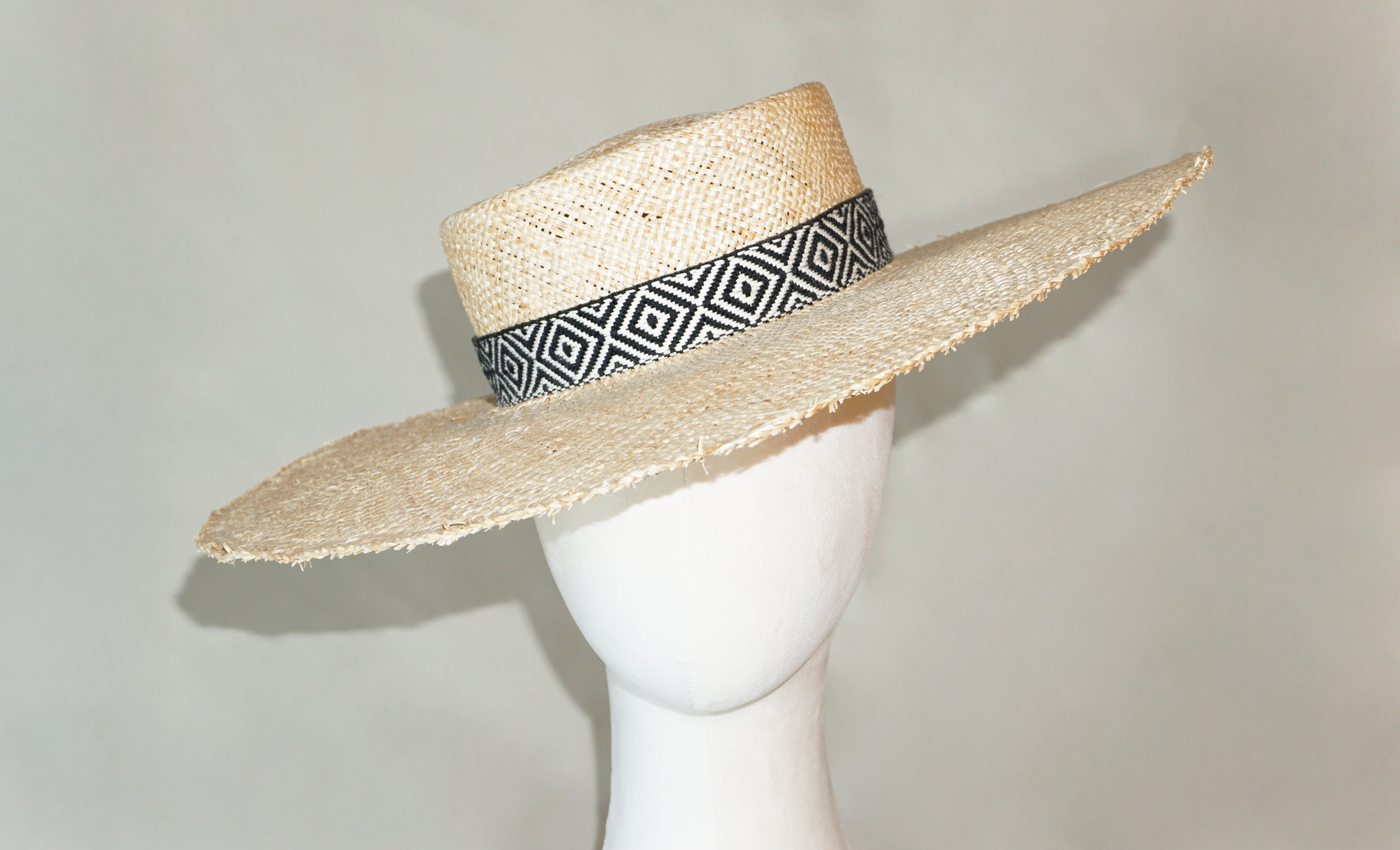 Delos handmade wide brim boater hat, pork pie crown, natural raffia straw,   woven black & ivory geometric band with back bow, front close view by Anna Xaniotaki 