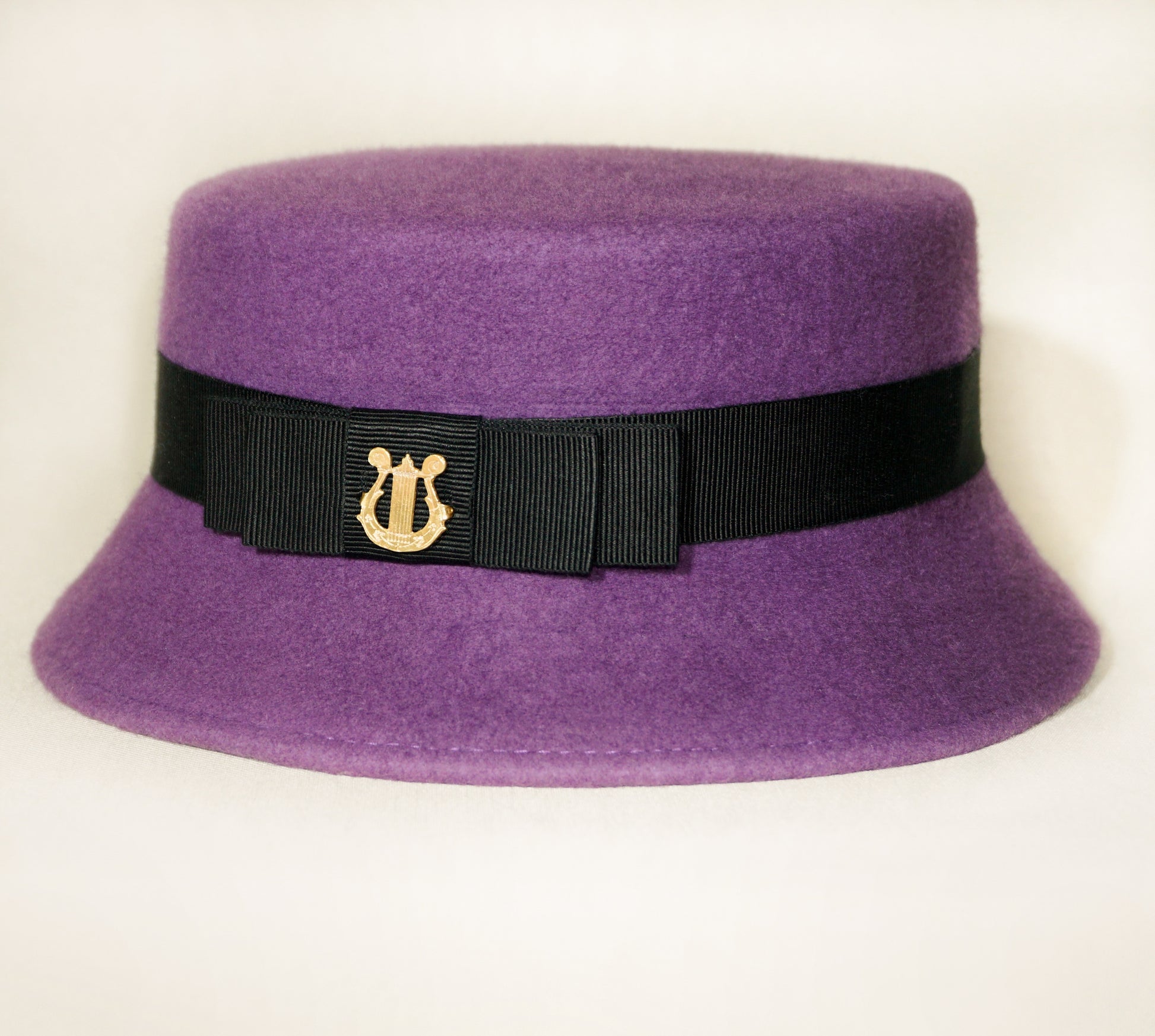  Aristocratic Melody Pillbox Hat in Royal Purple Wool Felt with Black Double Bow and Gold Lyre by Anna Xaniotaki - three-quarter front left view