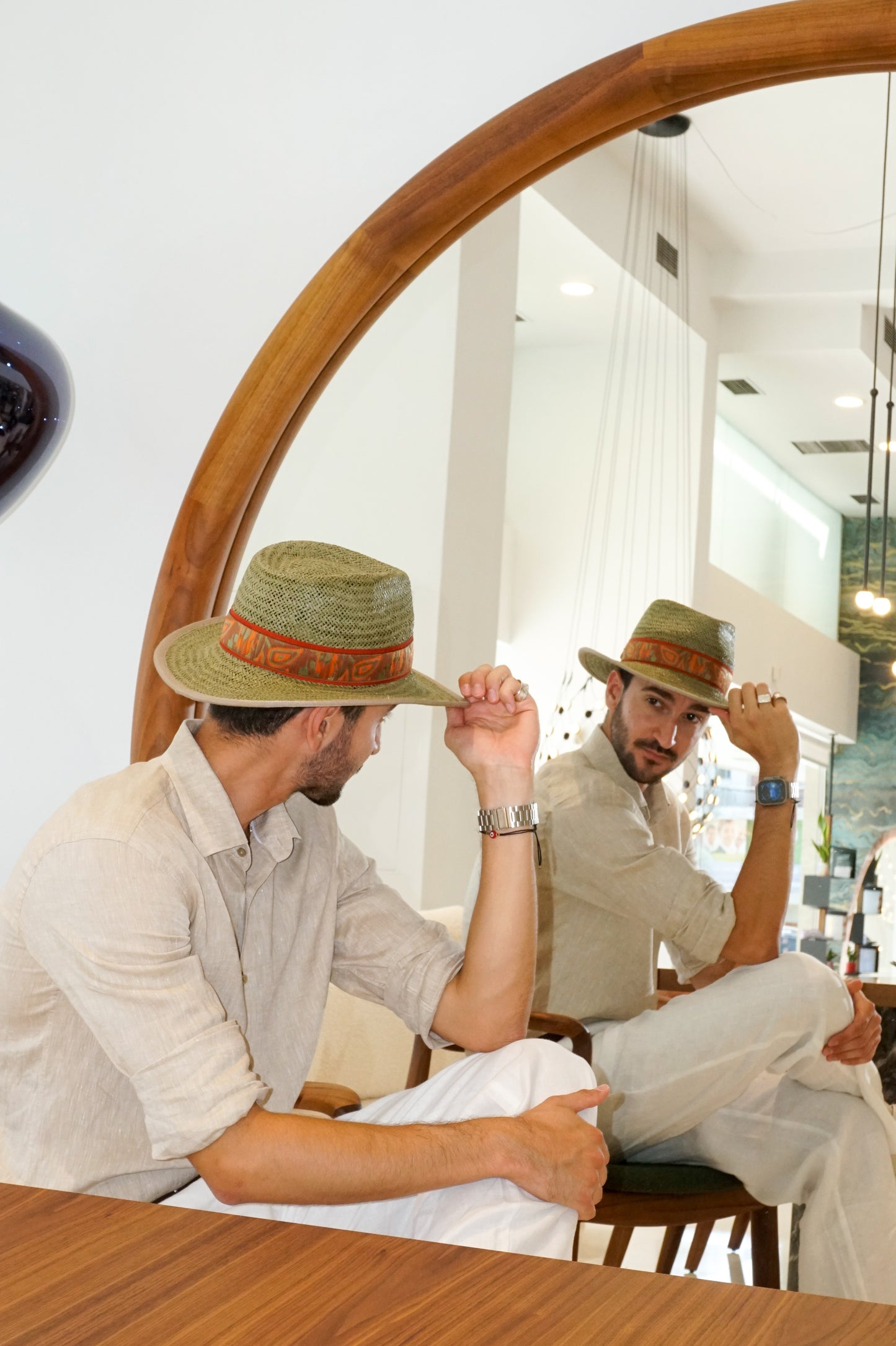 Man wearing the Indy Safari Fedora Hat in olive green paper straw with coral Italian cotton grosgrain ribbon and woven orange, coral and green band, photographed in a mirror reflection showing three-quarter right back side view and mirrored three-quarter left front view. Custom made-to-order fedora for summer special occasions, garden parties, vacations or for everyday man's elegance. Bespoke couture millinery by Anna Xaniotaki