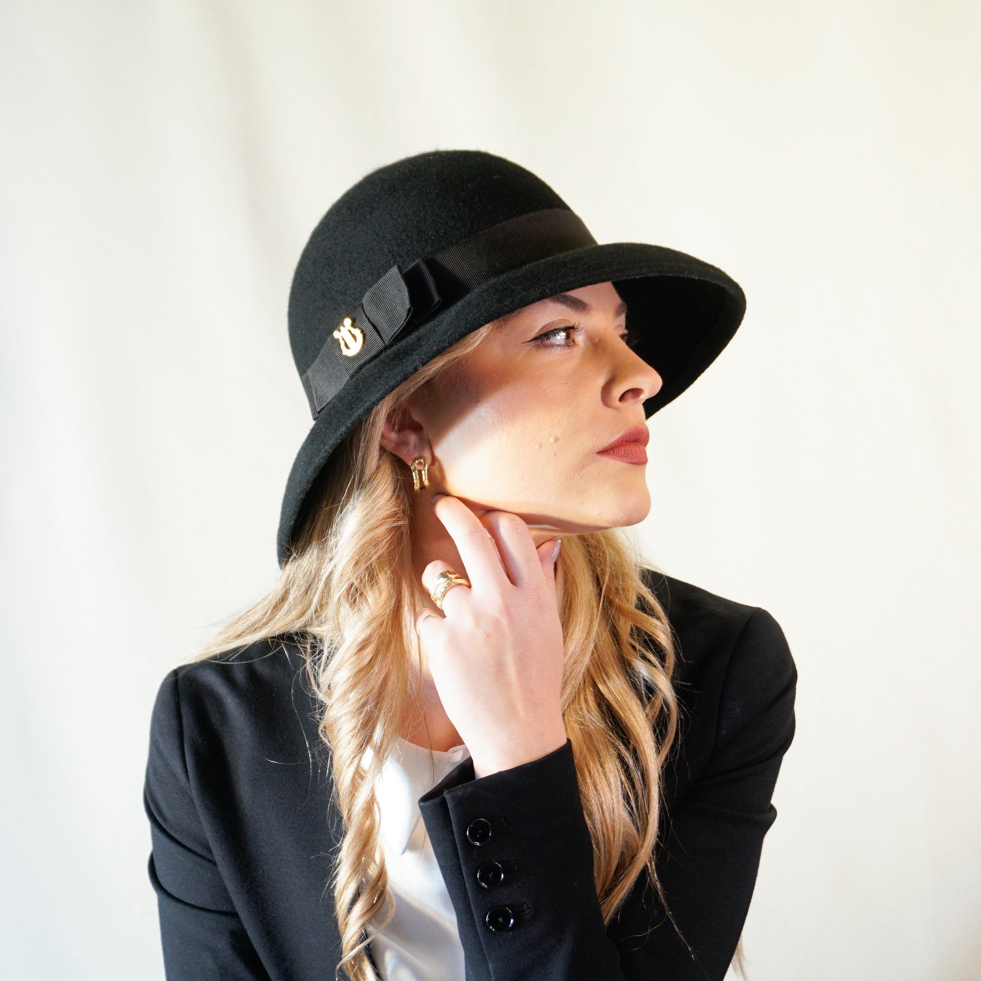 Noir Elegance Hat in Wool Felt with Bow and Gold Lyre by Anna Xaniotaki - three-quarter view