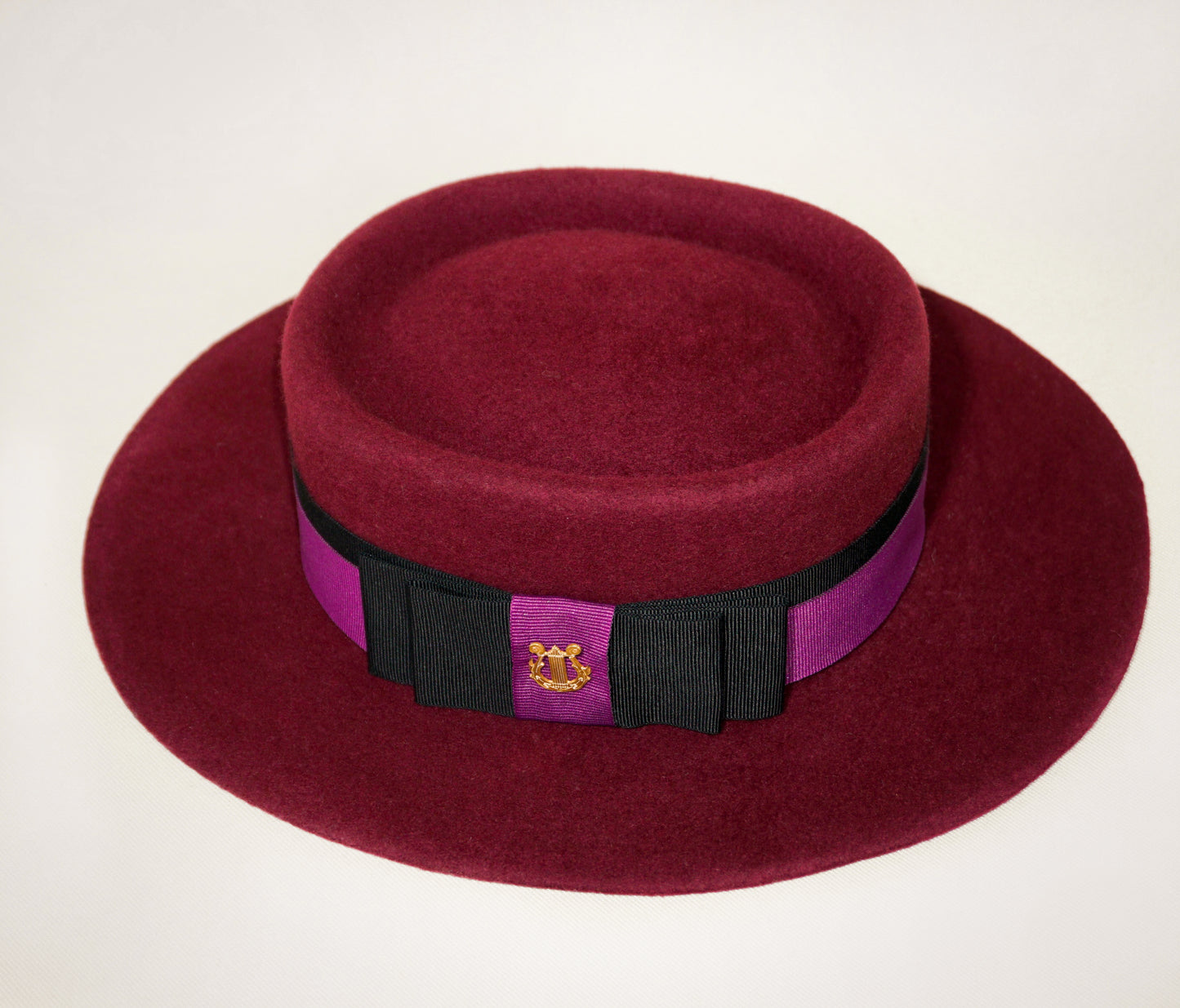 Right side view of Scarlet Ode burgundy boater hat with black and orchid purple ribbons, double bow and golden lyre