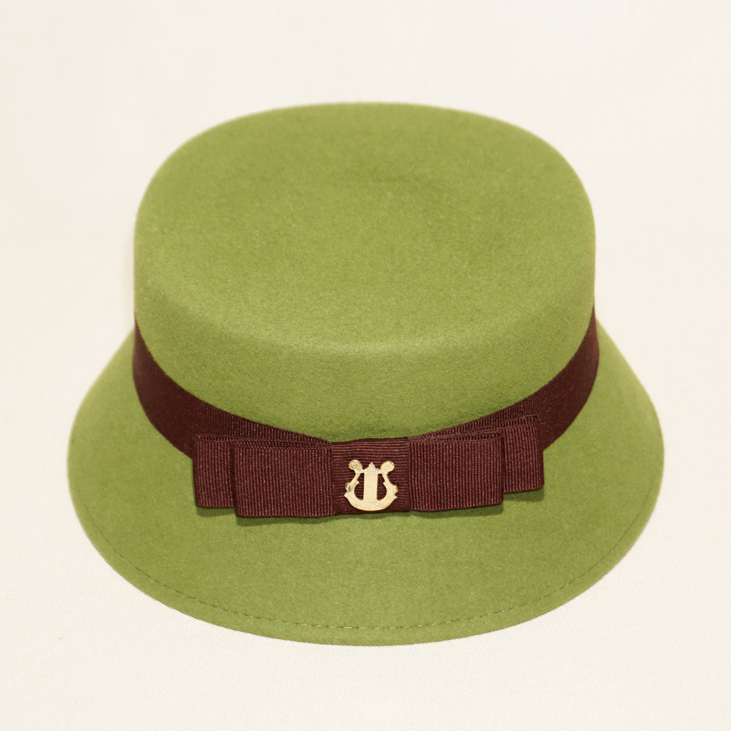 Aristocratic Melody lime pillbox felt hat by Anna Xaniotaki - close-up detail of double burgundy bow and 14ct gold-plated silver lyre