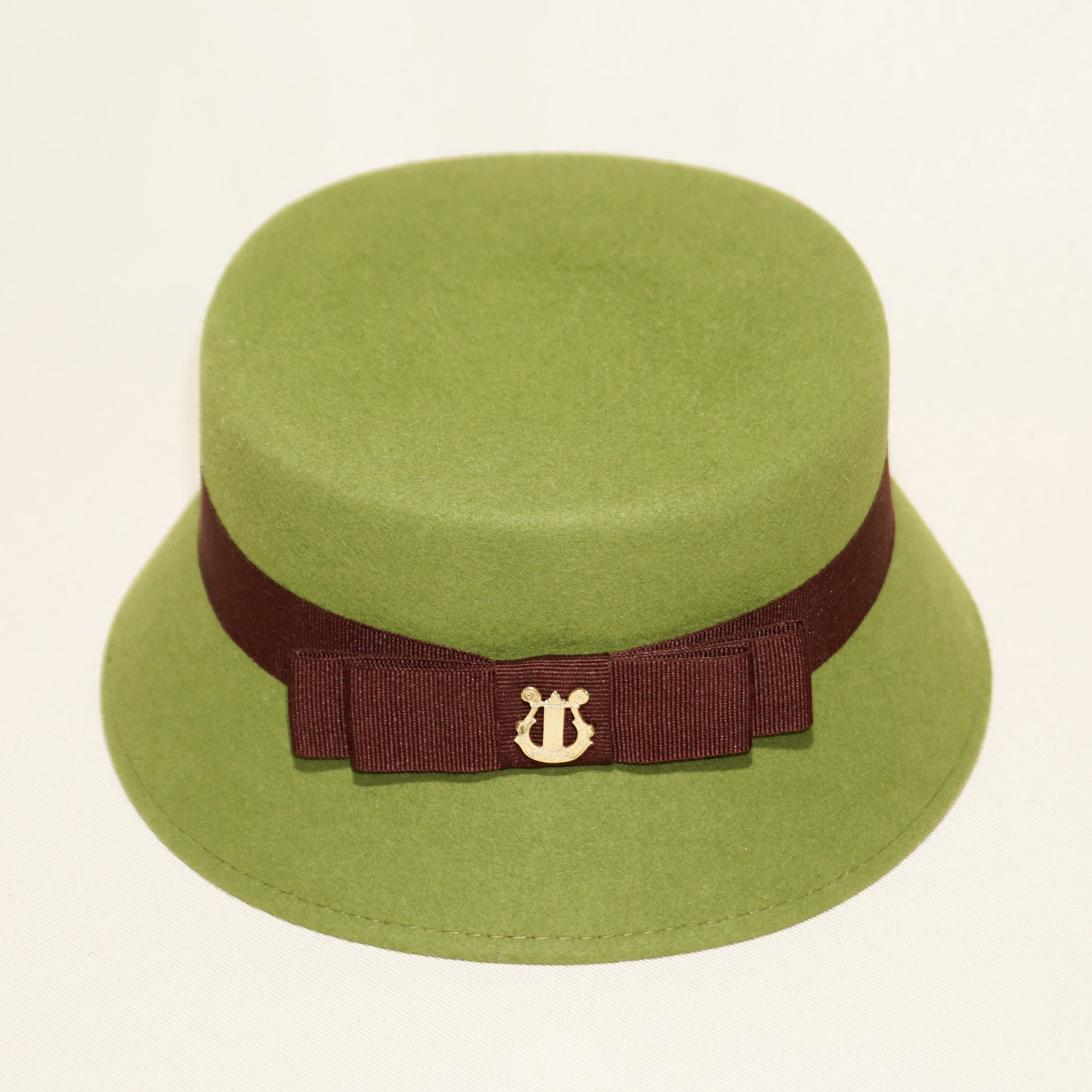 Aristocratic Melody lime pillbox felt hat by Anna Xaniotaki - close-up detail of double burgundy bow and 14ct gold-plated silver lyre