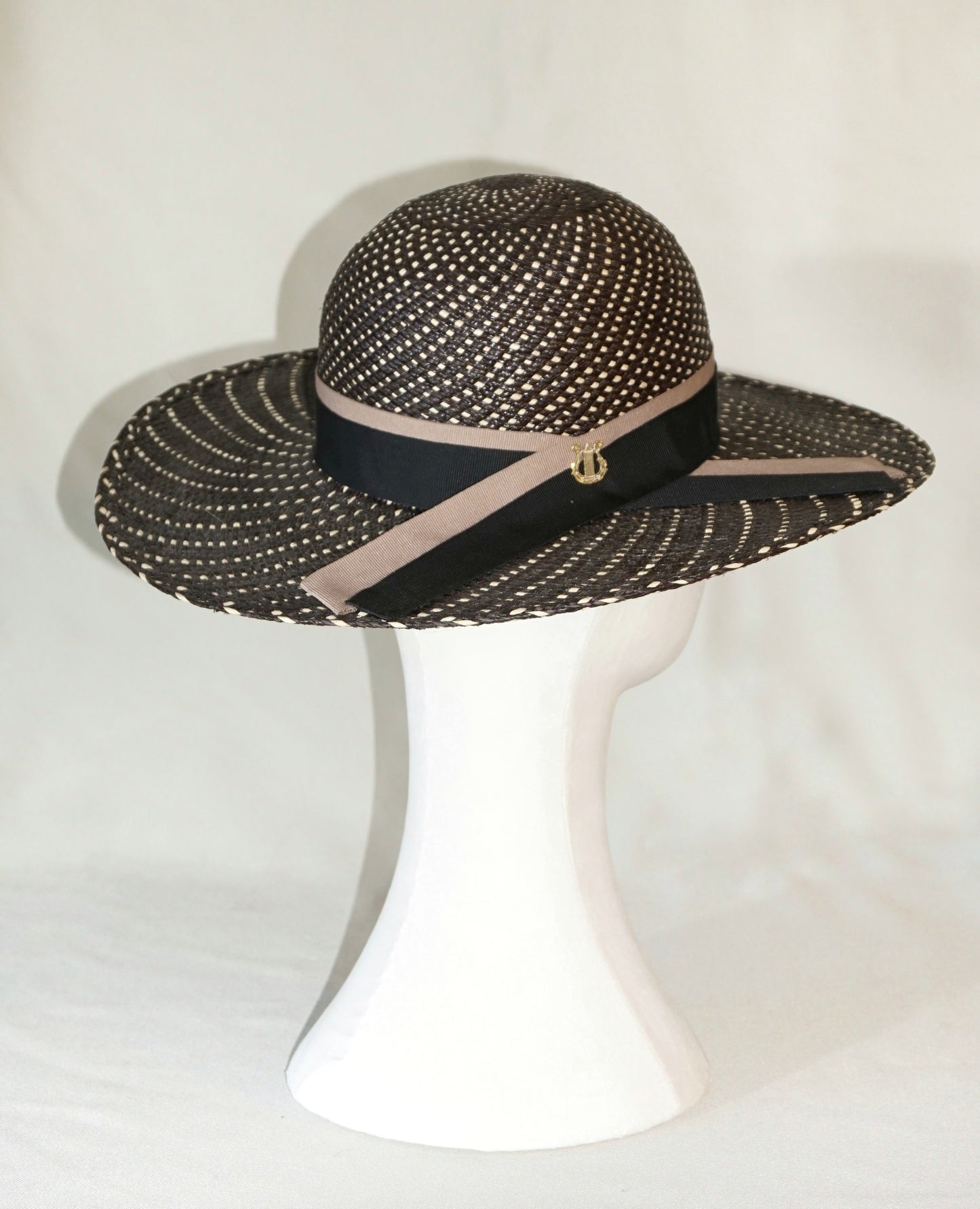 Black and ivory Panama hat with dual-tone ribbon and gold lyre, three-quarter back view by Anna Xaniotaki 
